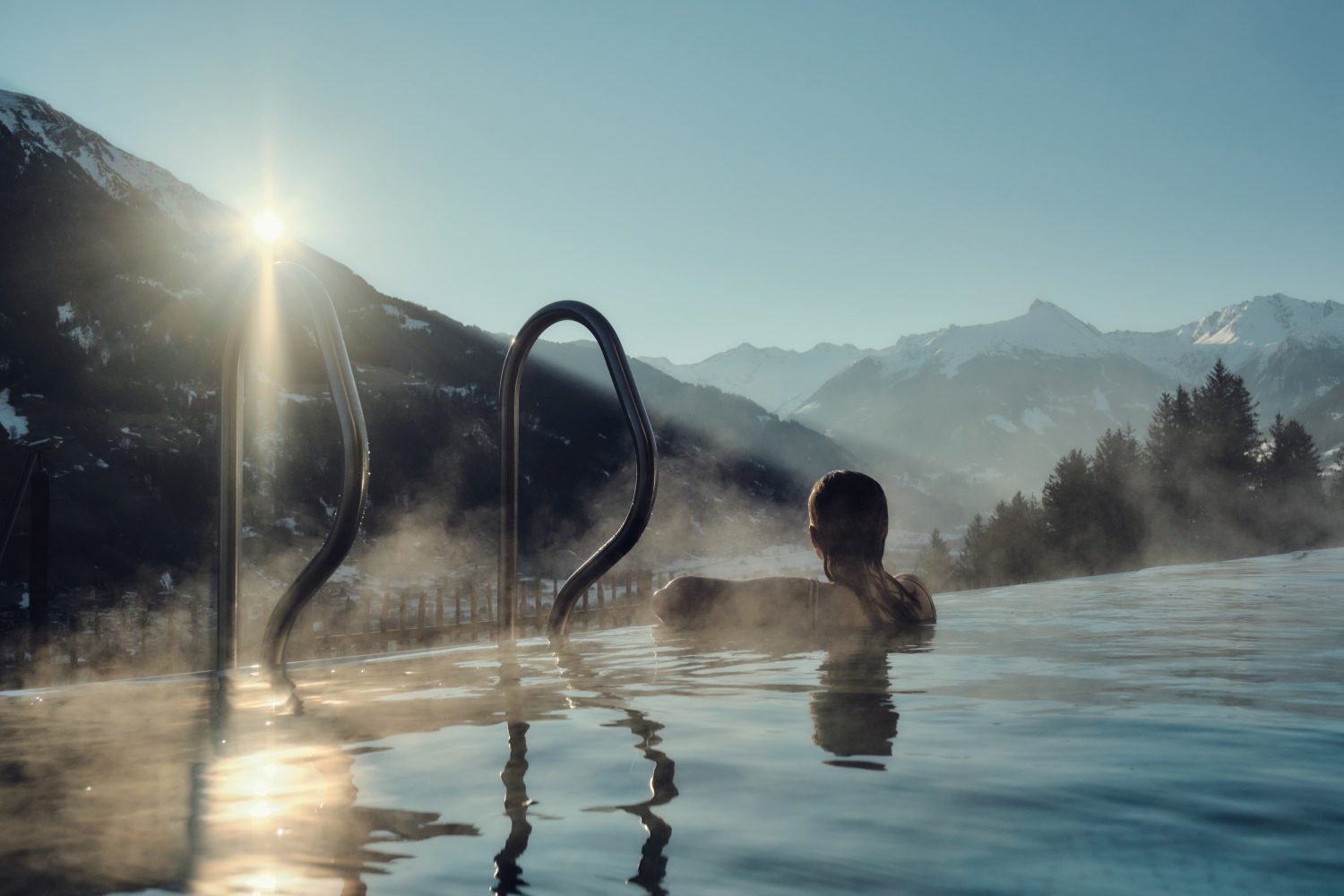 Woman in pool looking out at snow scene